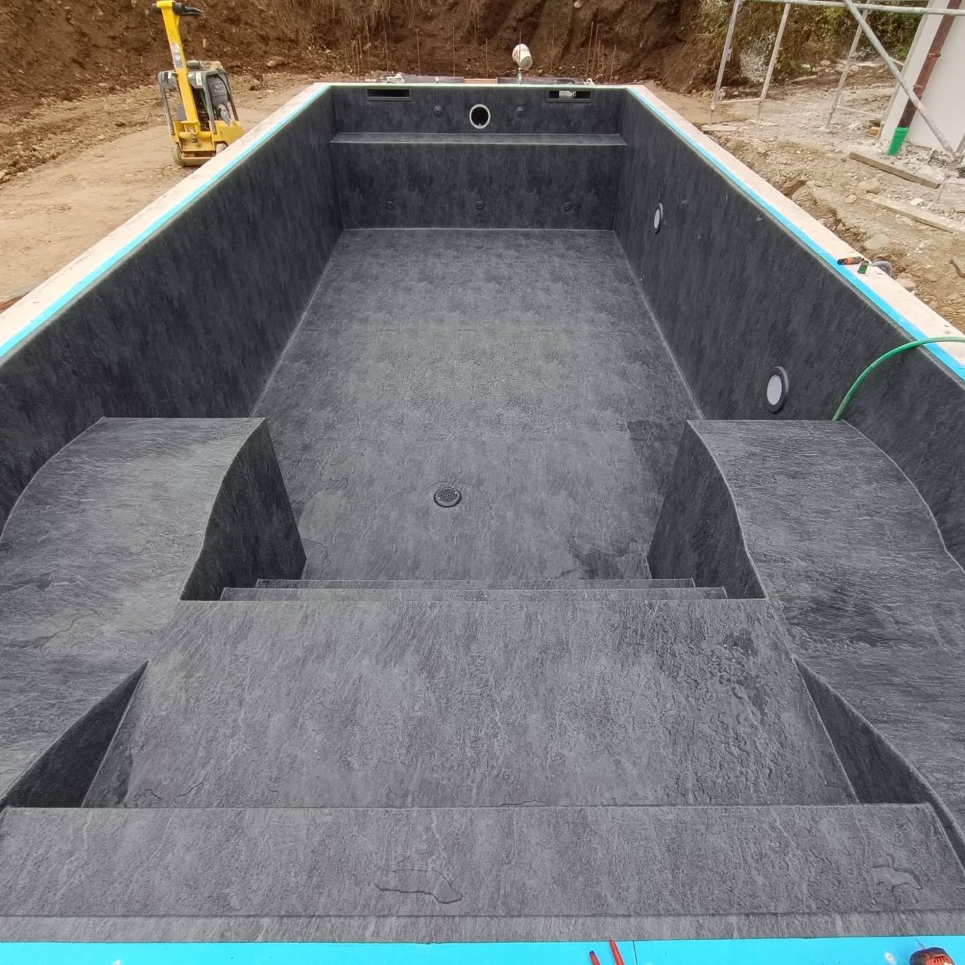 Poolbau im Oktober: fertige Poolwanne mit anthrazitfarbener Folie und Treppe
