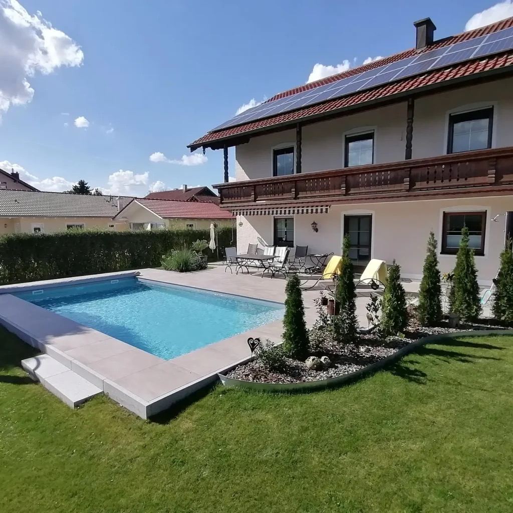 Hellblauer Pool vor Einfamilienhaus mit Rasen